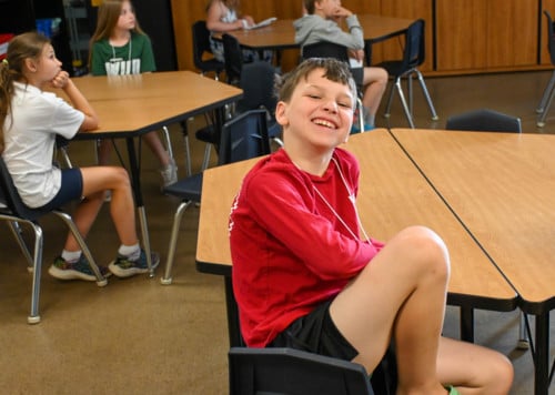 student sitting at desk and smiling at camera